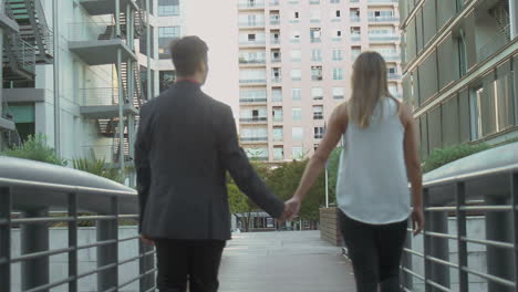Young-couple-holding-hands-on-urban-city-street