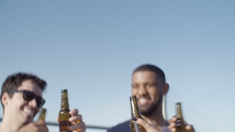 Amigos-Sonrientes-Tintineando-Botellas-De-Cerveza-Durante-Las-Vacaciones.