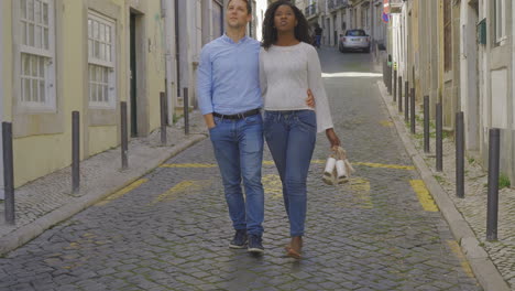 Happy-multiracial-couple-walking-on-street-and-looking-around.
