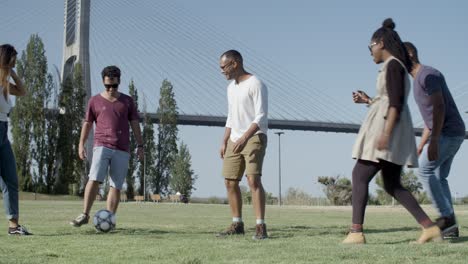 Group-of-five-happy-friends-playing-football-in-park.
