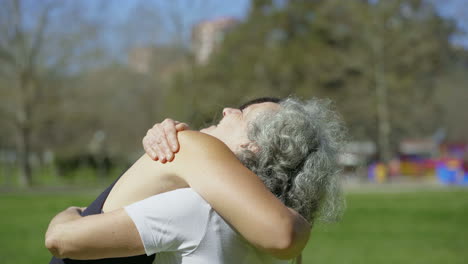 Smiling-senior-woman-hugging-with-sporty-young-girl-in-park.