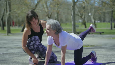 Smiling-senior-woman-with-young-trainer-during-workout-in-park.