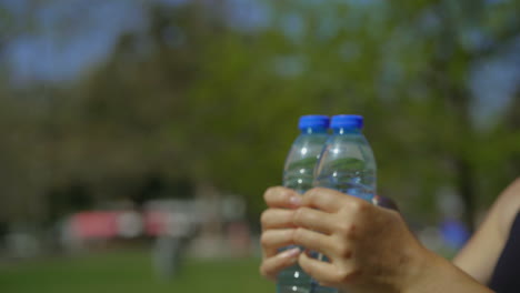 Frauenhände-Trainieren-Mit-Wasserflaschen