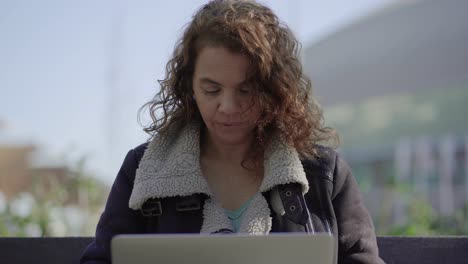 Smiling-mature-woman-using-laptop-outdoor