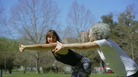 Two-women-doing-exercises-in-sunny-summer-park.
