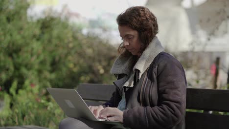 Focused-curly-female-freelancer-working-with-laptop-outdoor
