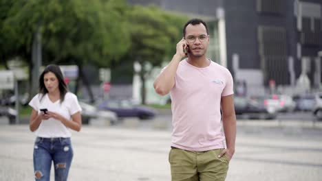 Handsome-man-talking-on-phone-while-walking-on-street