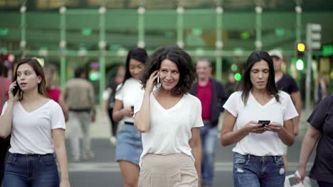 Smiling-mature-woman-talking-on-smartphone-during-stroll