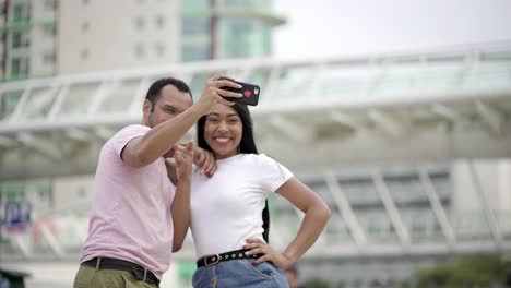 Happy-young-couple-posing-for-selfie-on-street