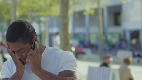Thoughtful-African-American-guy-talking-on-phone-and-rubbing-face.
