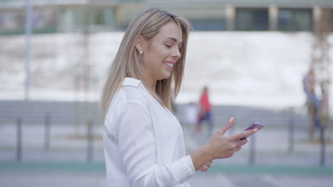 Mujer-Joven-Feliz-Usando-Un-Teléfono-Inteligente-Al-Aire-Libre