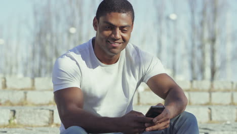 Hombre-Afroamericano-Sonriente-Sosteniendo-Un-Teléfono-Inteligente.