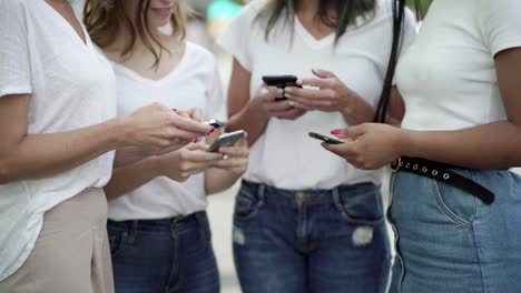 Focused-women-using-smartphones-on-street