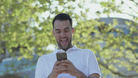 Young-bearded-man-holding-smartphone-and-laughing.