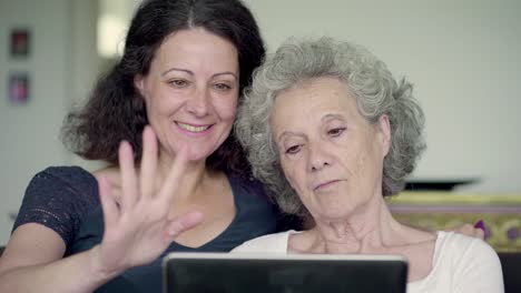 Daughter-and-mother-holding-tablet,-googling-and-swiping-photos