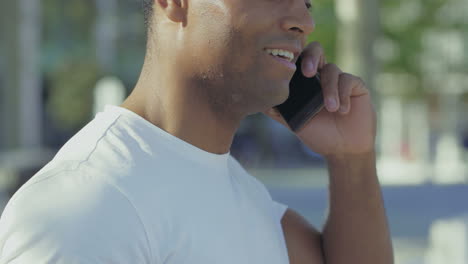 Side-view-of-smiling-guy-talking-on-smartphone.