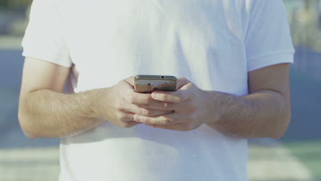 Ausgeschnittene-Aufnahme-Eines-Mannes-Im-Weißen-T-Shirt,-Der-Sein-Smartphone-Benutzt.