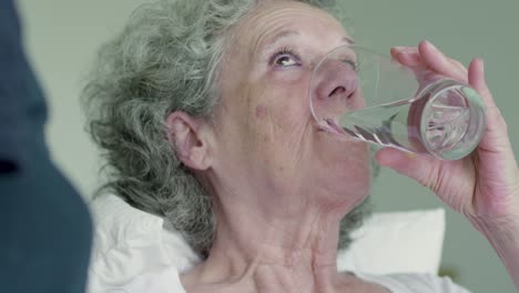 Nahaufnahme-Einer-Alten-Frau,-Die-Tabletten-Nimmt-Und-Wasser-Trinkt