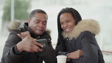 Afro-American-girl-with-braids-and-Afro-American-middle-aged-man-in-jacket-with-fur-hood-having-video-chat-on-tablet