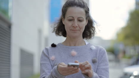 Front-view-of-smiling-middle-aged-woman-using-smartphone.