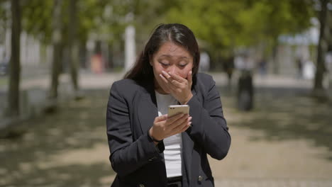 Shocked-girl-using-mobile-phone-on-street