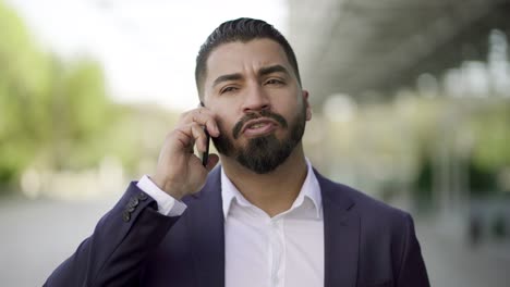 Serious-businessman-talking-by-mobile-phone-outdoor