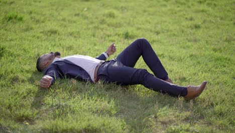Man-in-suit-lying-on-green-lawn