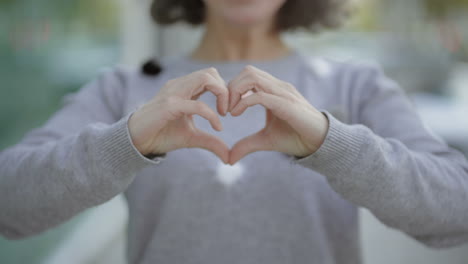 Cropped-shot-of-woman-making-heart-shape-with-hands