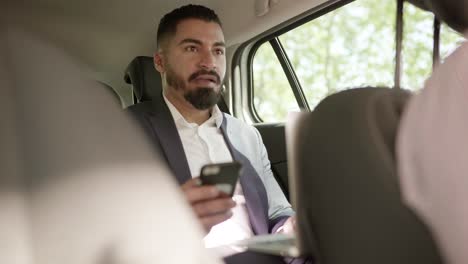 Man-using-laptop-and-smartphone-in-car