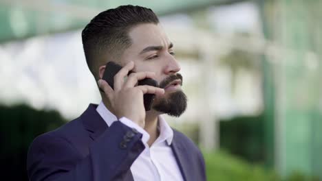 Businessman-talking-by-cell-phone-and-looking-away-outdoor