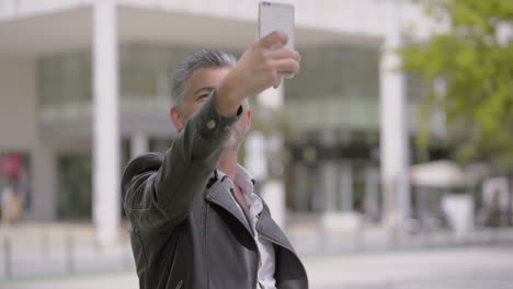 Mature-man-taking-selfie-with-smartphone-on-street