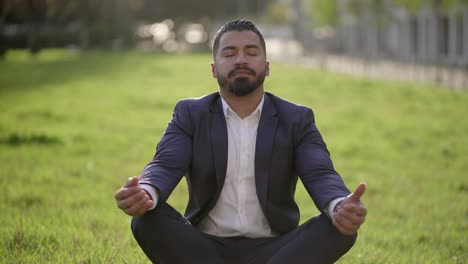 Businessman-in-suit-meditating-on-green-grass