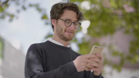 Hombre-Sonriente-Con-Anteojos-Usando-Un-Teléfono-Inteligente