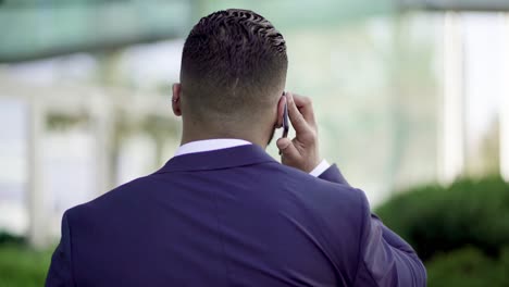 Back-view-of-businessman-talking-by-cell-phone-outdoor