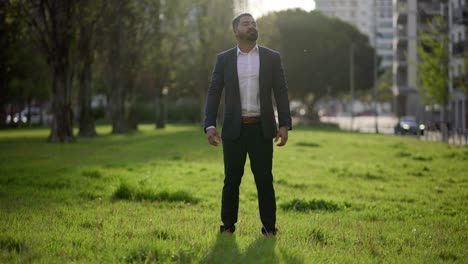 Happy-businessman-standing-on-green-lawn