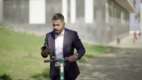 Businessman-riding-scooter-and-answering-phone-call