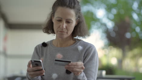Concentrated-middle-aged-woman-holding-phone-and-credit-card