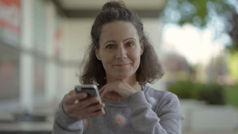 Lächelnde-Frau-Mittleren-Alters,-Die-Ihr-Smartphone-Auf-Der-Straße-Benutzt.
