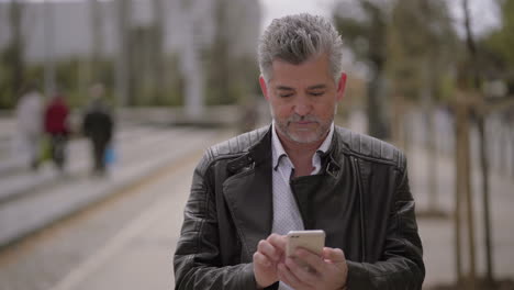 Focused-mature-man-using-smartphone-outdoor