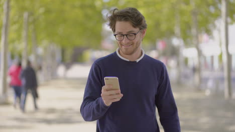 Happy-man-in-eyeglasses-using-cell-phone-outdoor