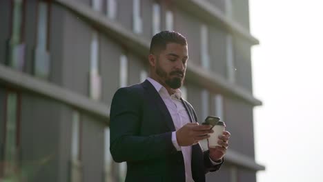Geschäftsmann-Hält-Pappbecher-In-Der-Hand-Und-Benutzt-Smartphone-Im-Freien