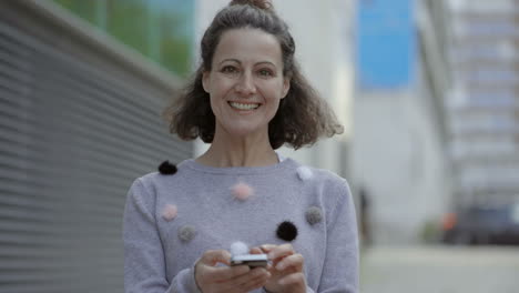 Happy-middle-aged-woman-using-smartphone-outdoor.