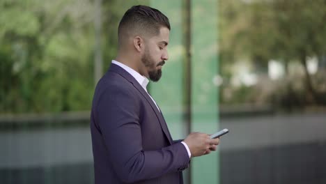 Side-view-of-businessman-messaging-by-smartphone