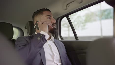 Serious-businessman-using-mobile-phone-in-car