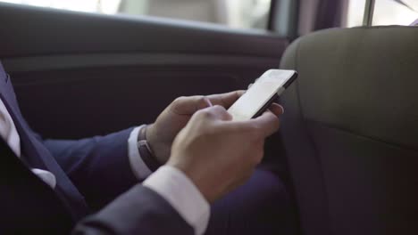 Cropped-shot-of-businessman-using-smartphone-in-car