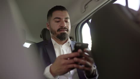Smiling-businessman-using-cell-phone-in-car