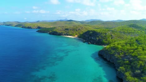 Aerial-dolly-tilt-up-reveals-gorgeous-blue-waters-of-San-juan-playa-beach,-curacao-caribbean