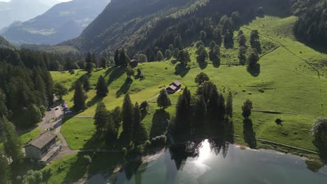 Sun-reflection-on-a-beautiful-lake-in-summer-swiss-in-a-scenic-drone-shot-on-wooden-cottage-in-a-small-rural-area-town-nafels-obersee-switzeland-travel-in-summer-season-to-wonderful-nature-landscape