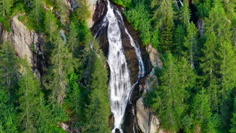 Wonderful-aerial-view-of-waterfall-on-ripid-mountain-wall-surrounded-by-trees