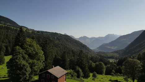 Die-Malerische-Landschaft-Einer-Rotbraunen-Holzhütte-Im-Alpengebirgswald,-Ein-Hochlandwald,-Sorgt-Für-Einen-Wunderbaren-Sonnenuntergang-An-Einem-Halb-Bewölkten,-Dunstigen-Tageslandschaftshintergrund-Auf-Reisen-In-Die-Schweiz,-Nafels,-Obersee,-Niederurnen
